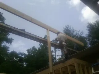 Carpenter setting a ridge beam over a new addition frame — Ice Dam Removal by Roofing Brothers in Water Mill