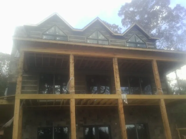 Dormers and porch framing on a large log home under construction — Roof Coating work by our crew in Water Mill
