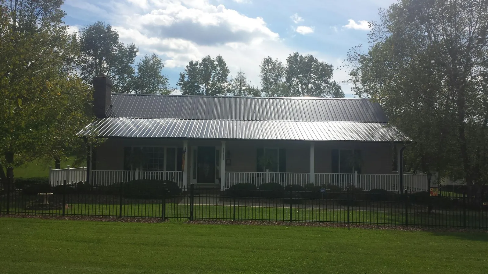 Gray metal roof on a brick ranch with a full width front porch — Gutter Guard Installation work by our crew in Water Mill