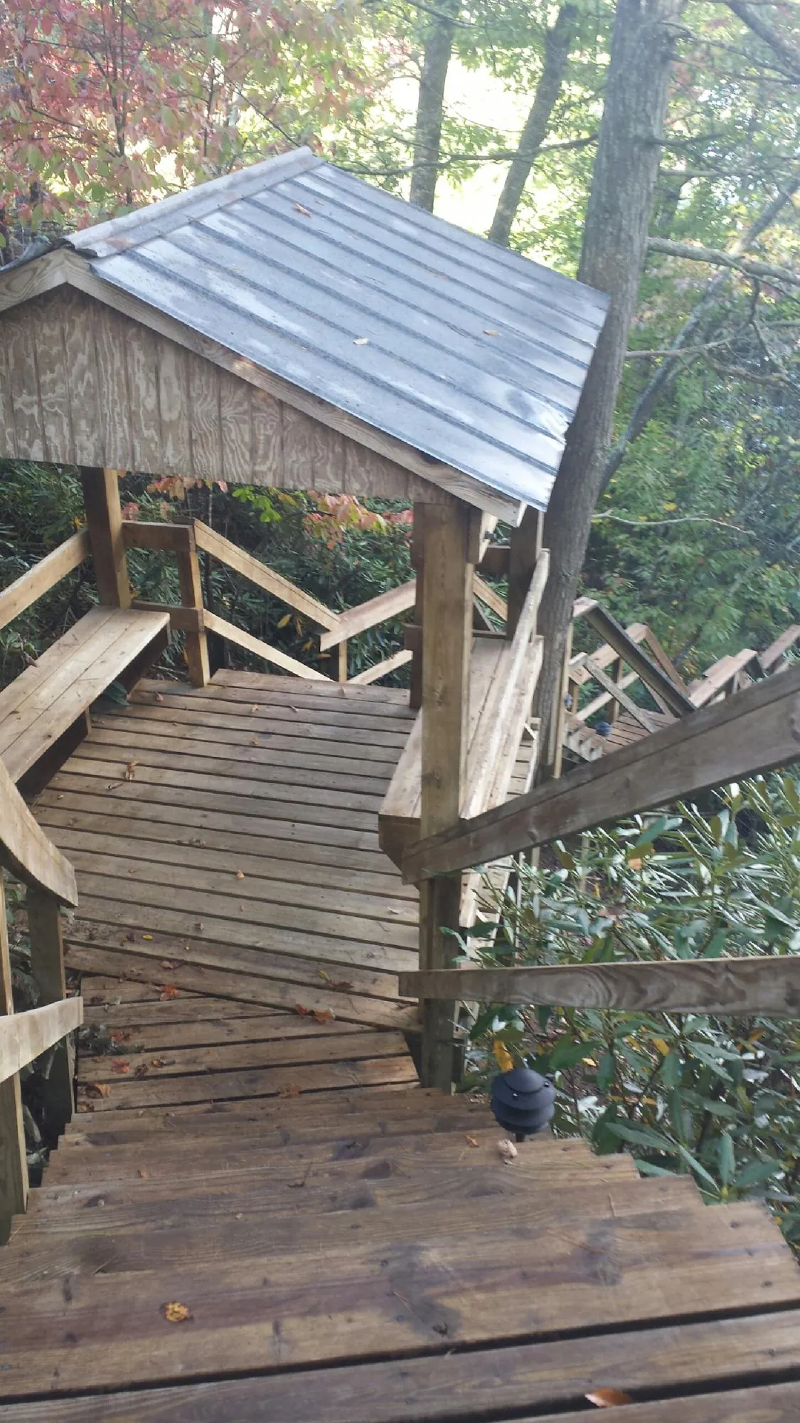 Metal roofed shelter over wooden steps on a wooded walkway — Skylight Repair & Installation work by our crew in Water Mill