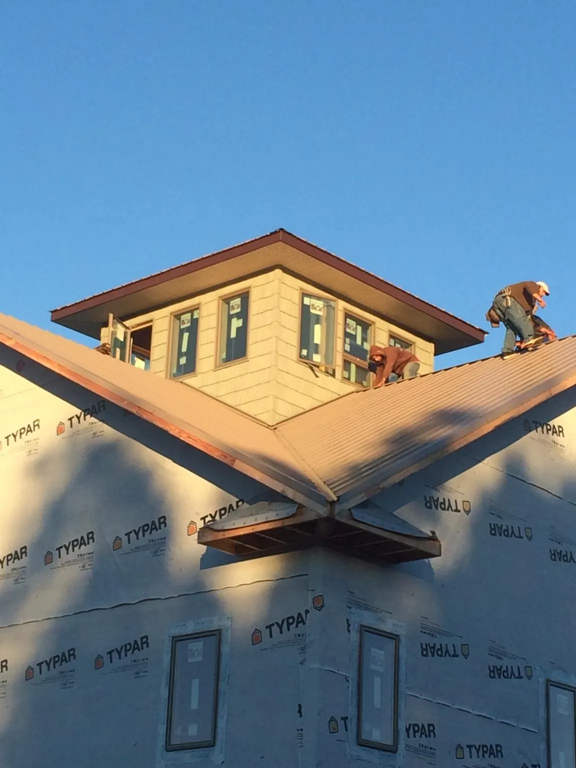 Roofers working around a rooftop cupola on a new metal roof at sunset — Roof Waterproofing in Water Mill by Roofing Brothers